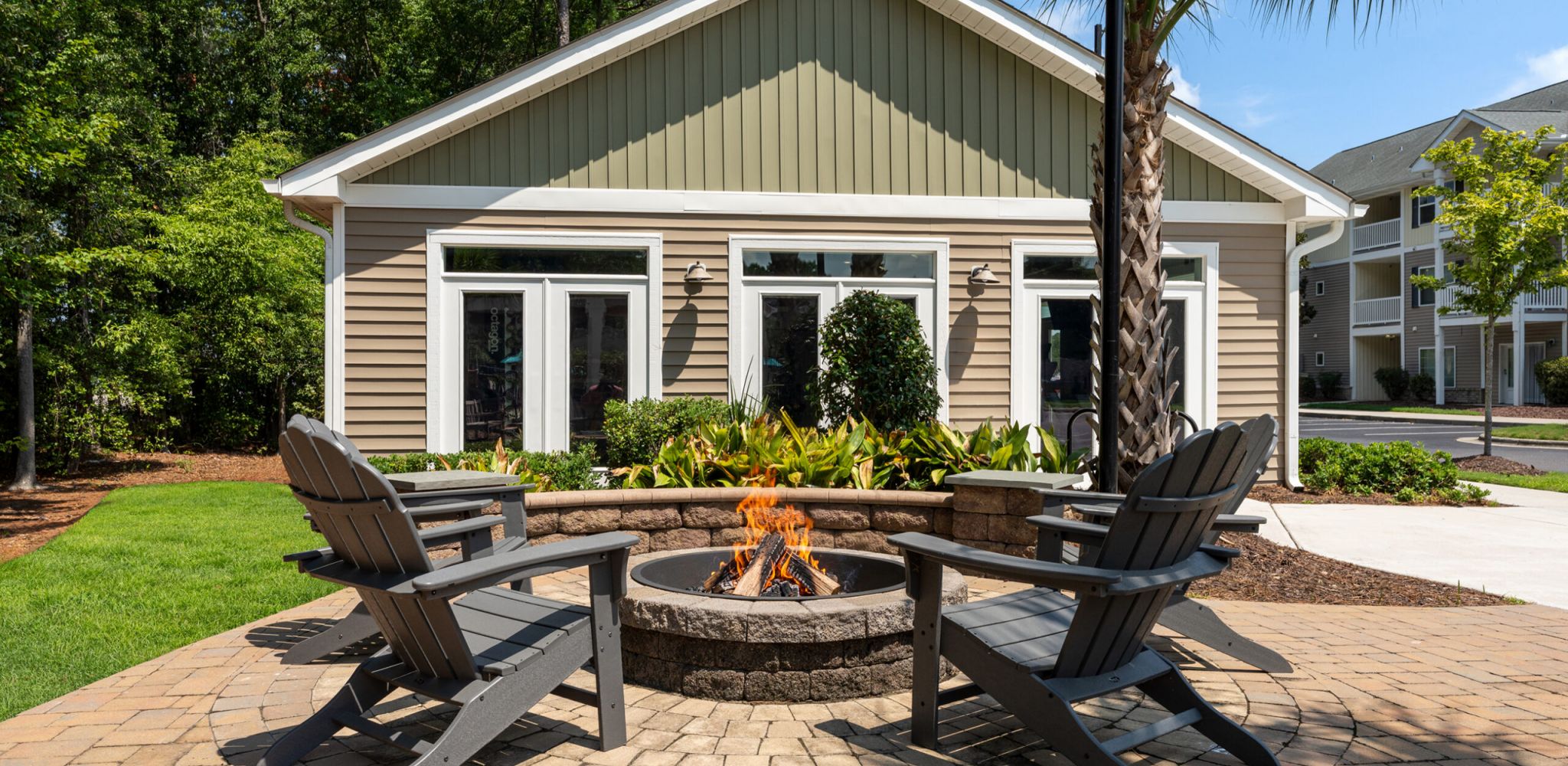 Hawthorne at Murrayville outdoor patio area with wooden chairs, a fire pit, and lush greenery surrounding the space