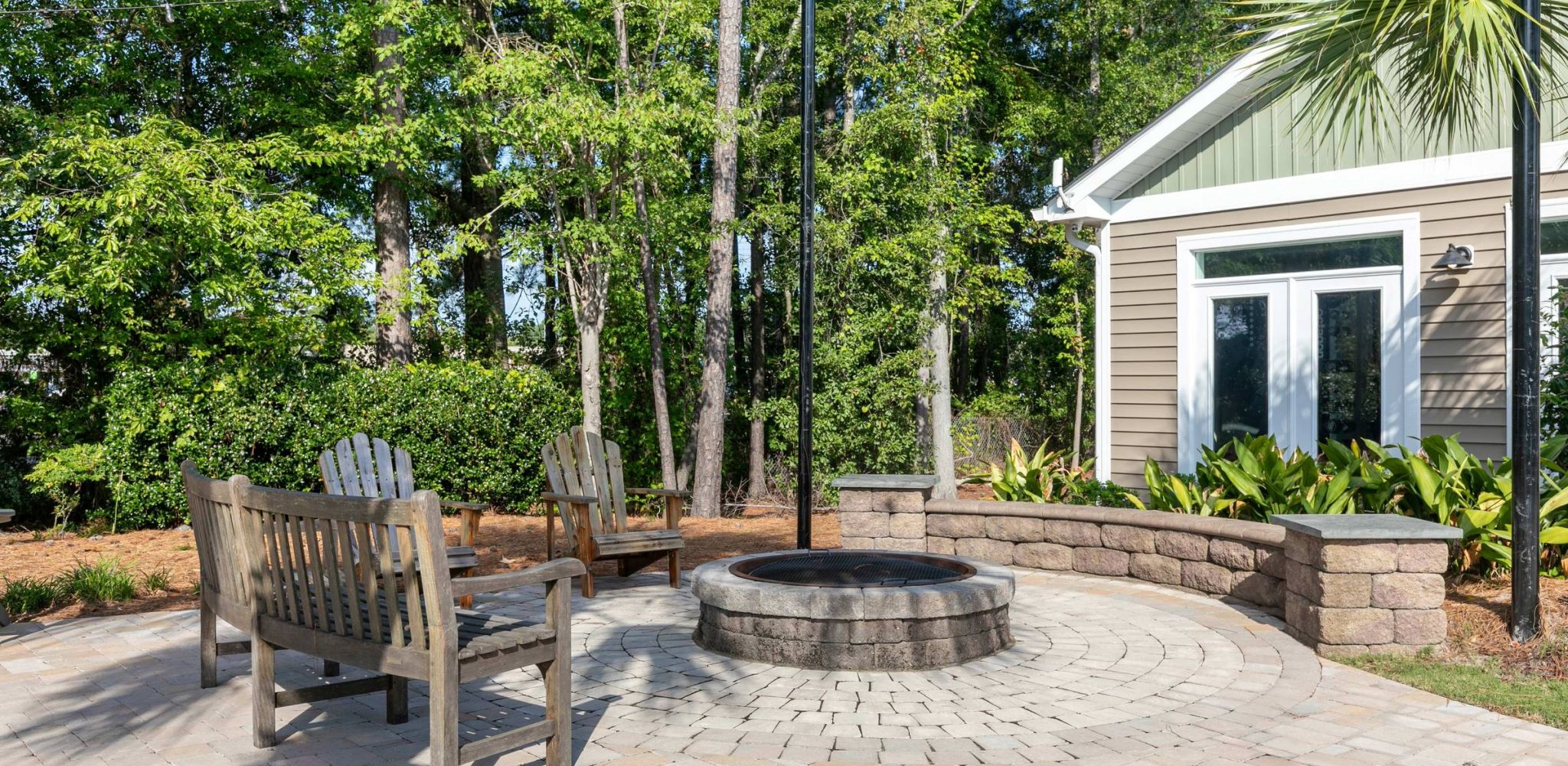 Hawthorne at Murrayville outdoor patio area with wooden chairs, a fire pit, and lush greenery surrounding the space